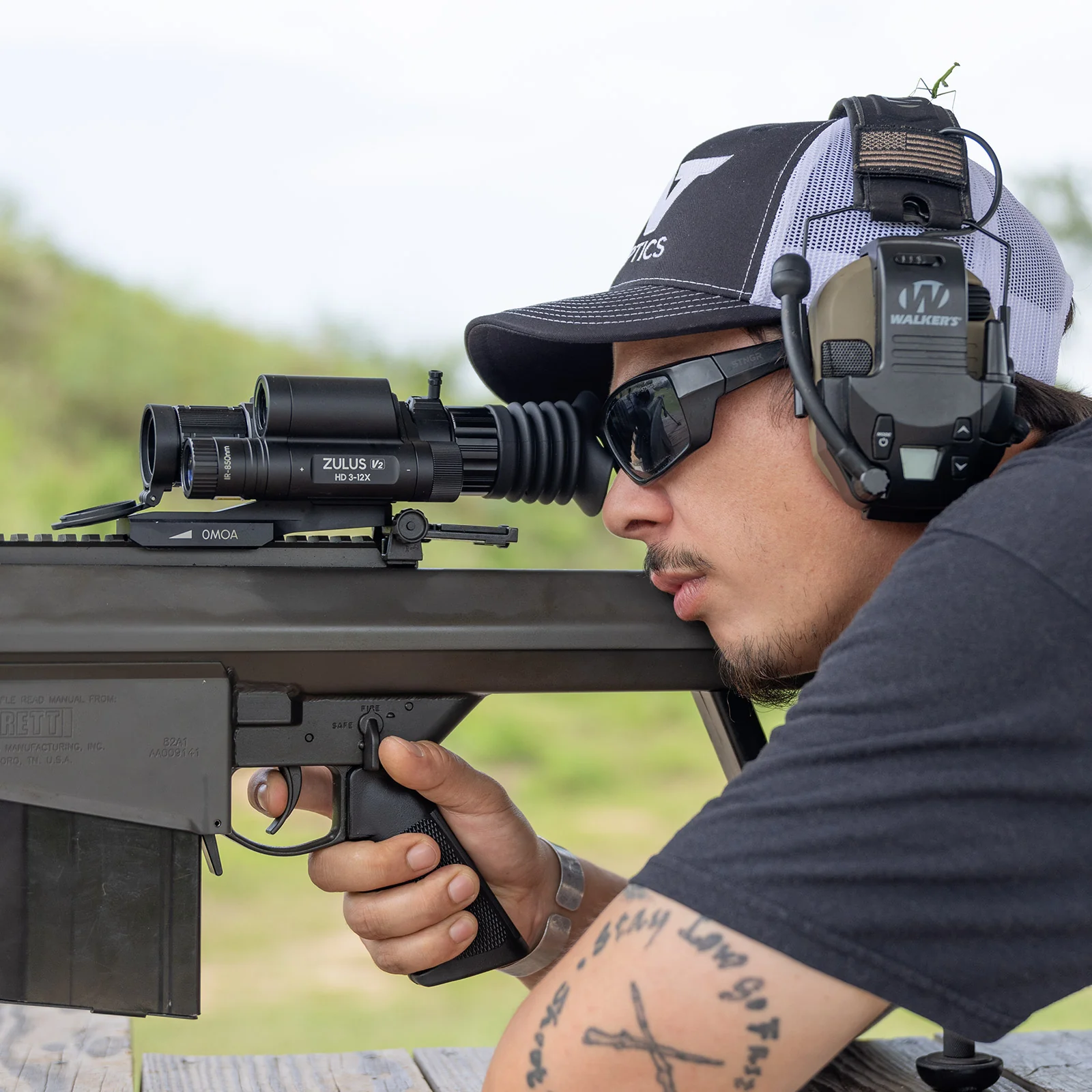 Shooter aiming a large-format rifle mounted with a DNT Optics ZHD312R-V2 scope, IR-850nm and HD 3-12X branding visible